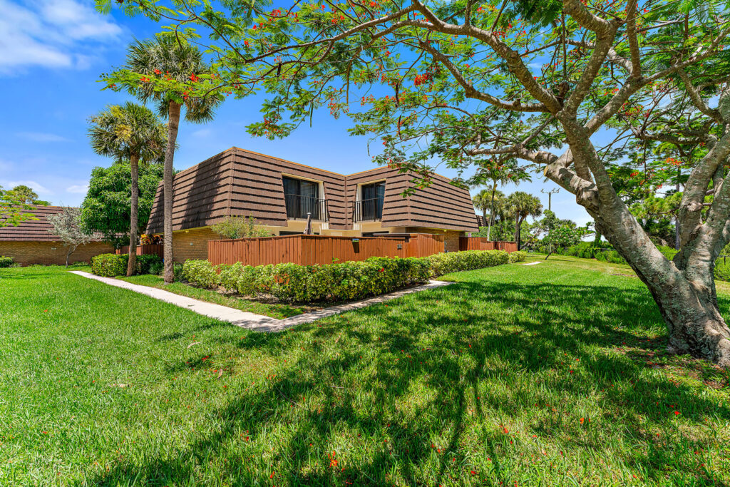 brown house surrounded by lush green field and trees
