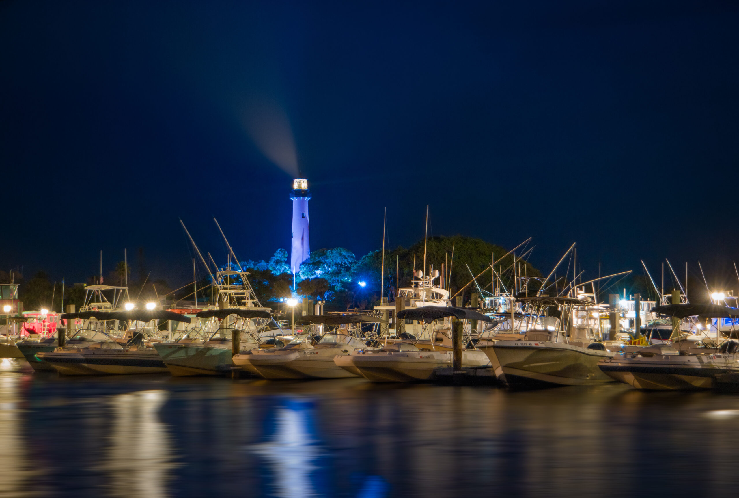 a row of docked boats with a lighthouse on the back