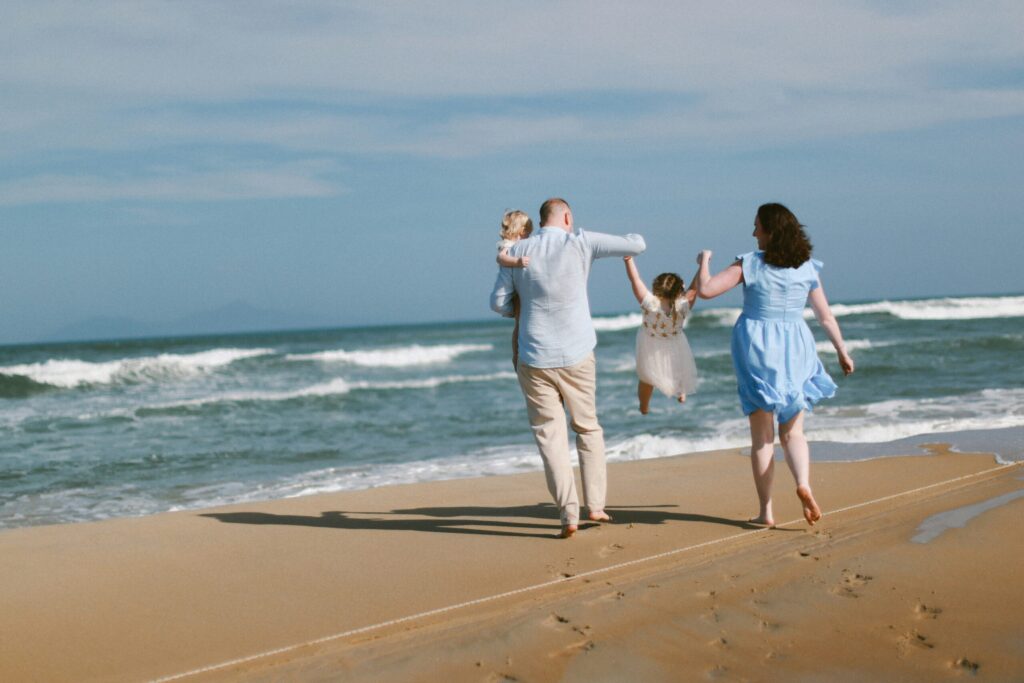 a family walking on the beachfront with ocean waves